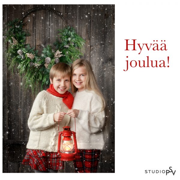 kaksi tyttöä pitelee pientä punaista öljylamppua jouluisen kranssin edessä joulukorttikuvassa.