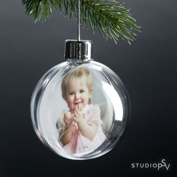 Pienen tytön kuva kirkkaan joulupallon sisällä.