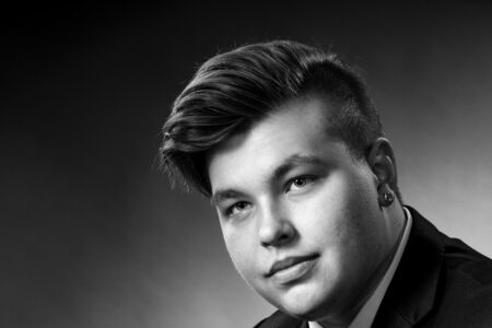 Mustavalkoinen lähikuva nuoresta miehestä puku päällä kädet yhdessä kyynärpäihin nojaten Studio P.S.V:n muotokuvassa.