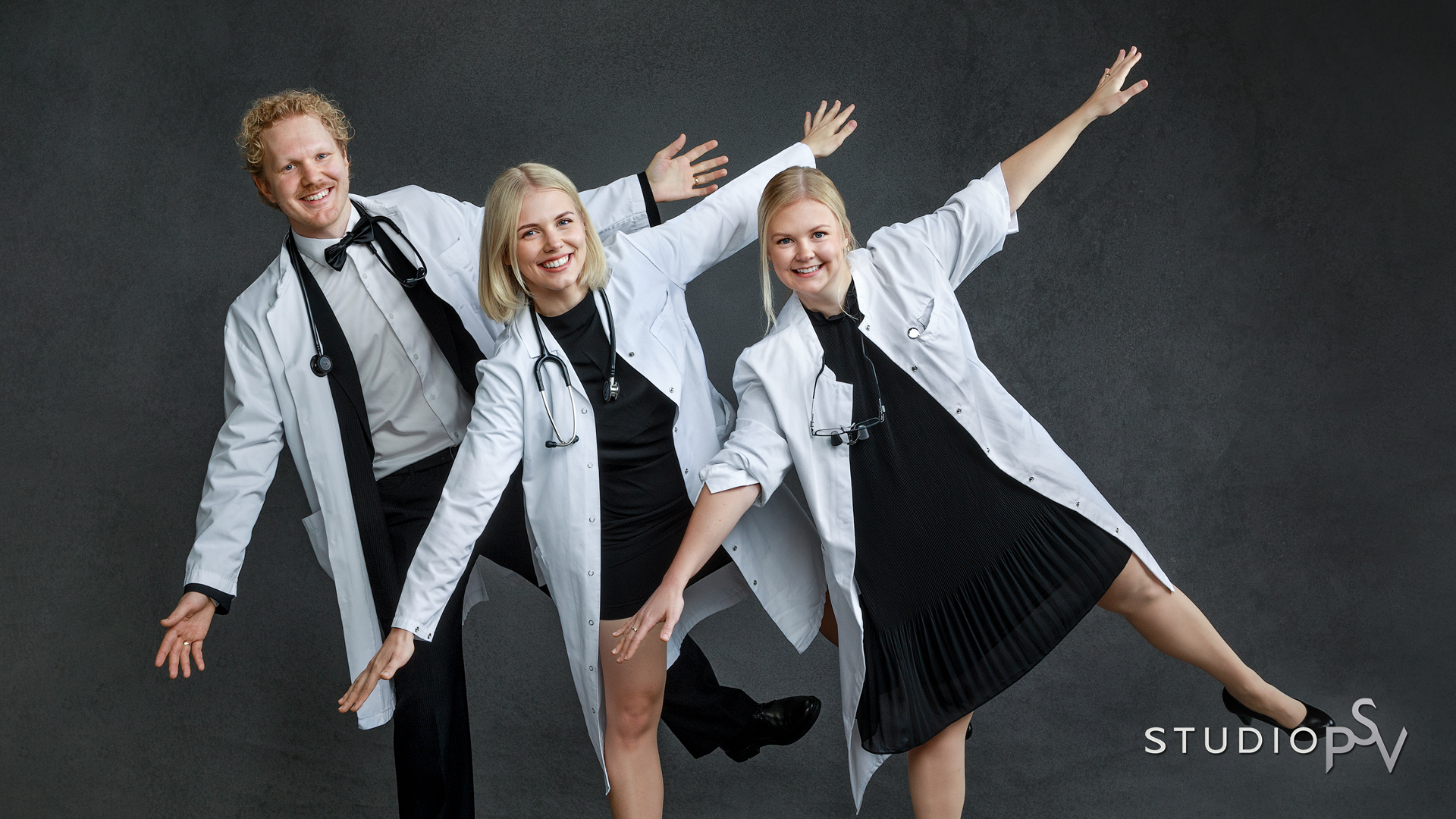 Kolme vasta valmistunutta nuorta lääkäriä poseeraa hauskassa ryhmäkuvassa