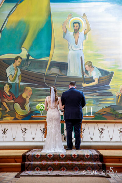 Hääpari kirkon alttarilla takaapäin kuvattuna